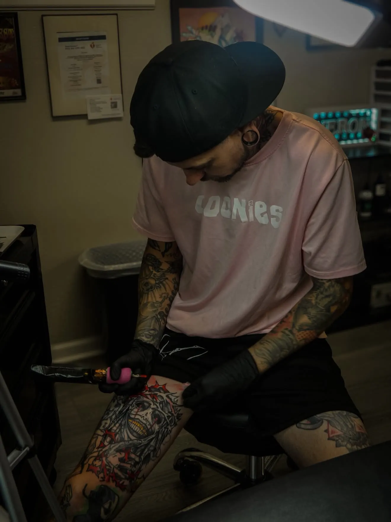 Cory Veron in black gloves, tattooing a leg
